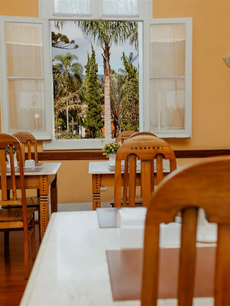 Salão de café com mesas de madeira e janelas