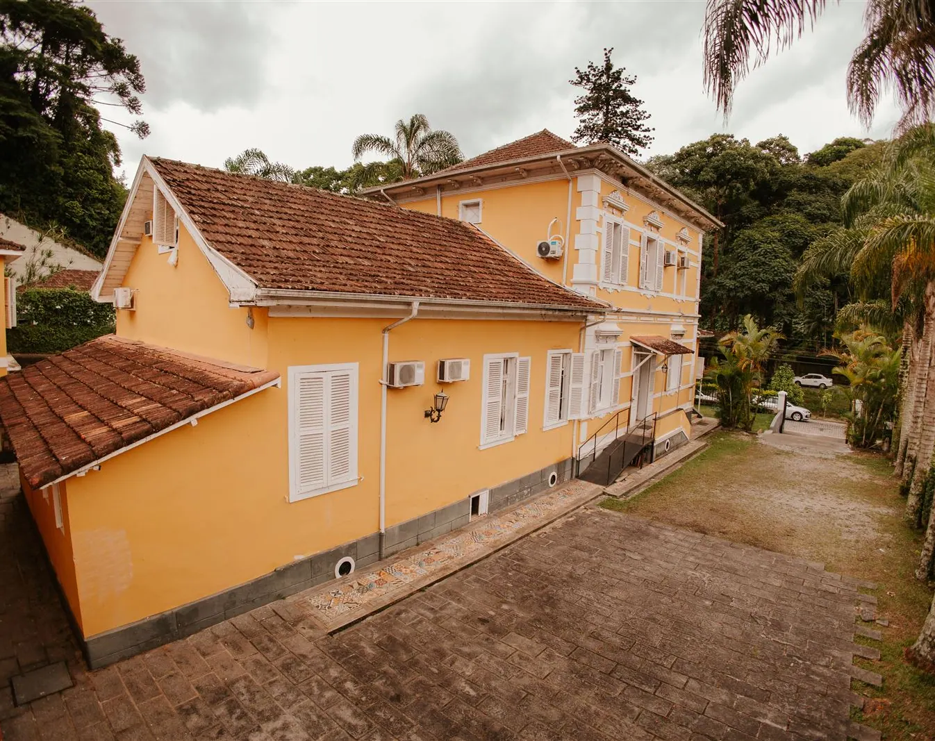 Vista do alto da casa colonial da pousada cercada de palmeiras