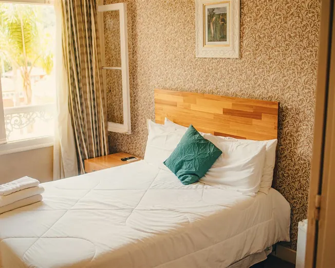 Quarto aconchegante com cama arrumada e janela
